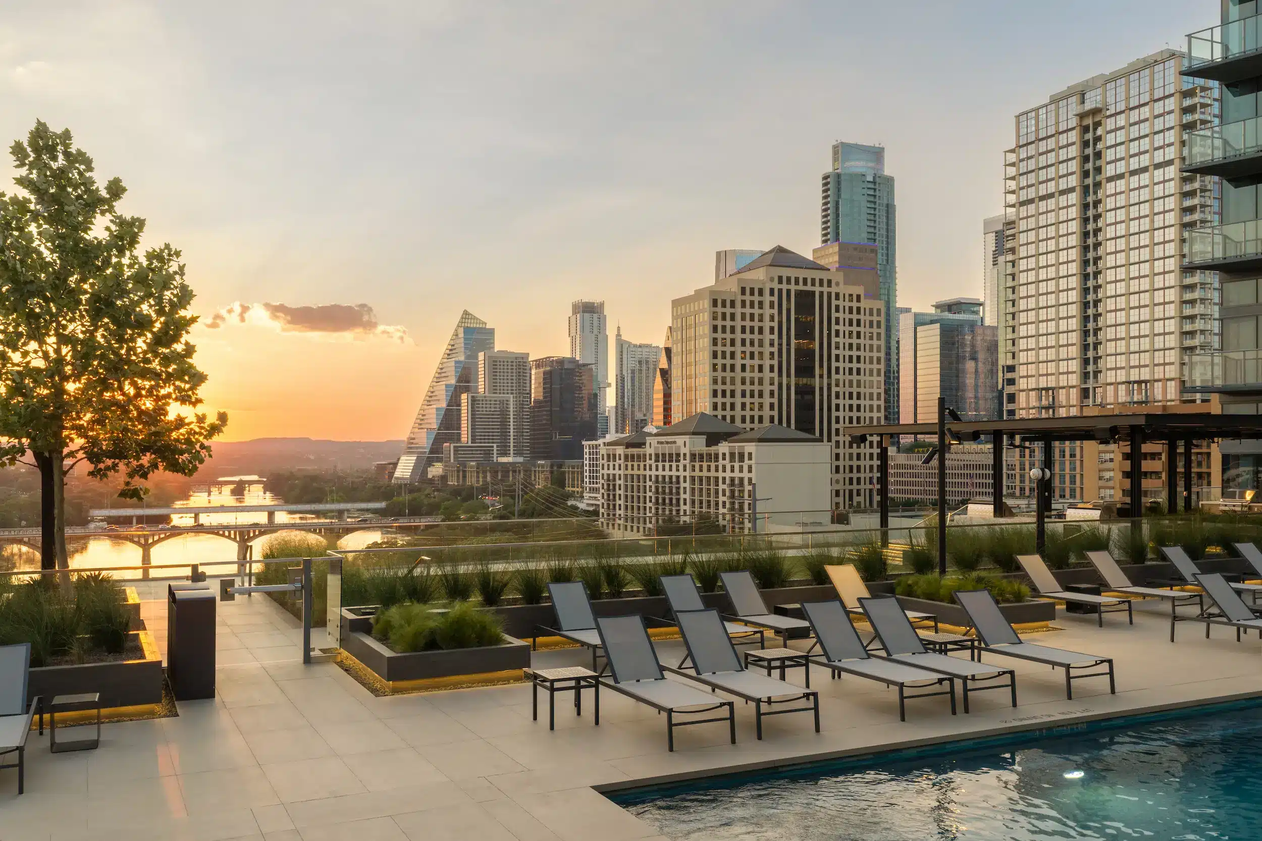 The Travis ATX pool deck with lounge chairs and the Austin skyline